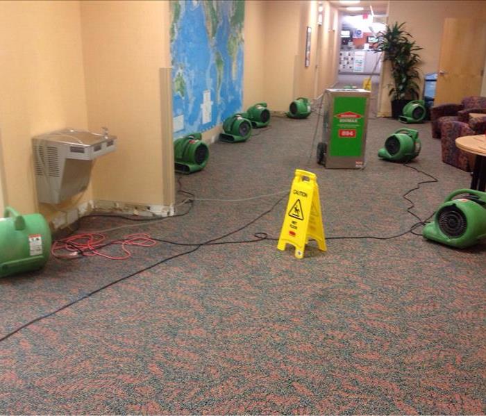 This picture shows a hallway in a school that had a water damage. SERVPRO equipment has been set in place to dry the area. 