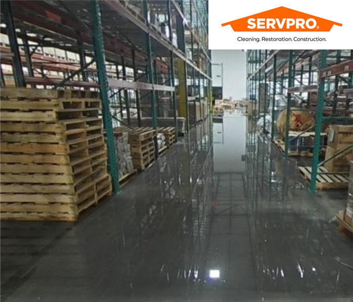 water damage overflowing in a warehouse featuring glossy floors and a SERVPRO of Indianapolis East logo